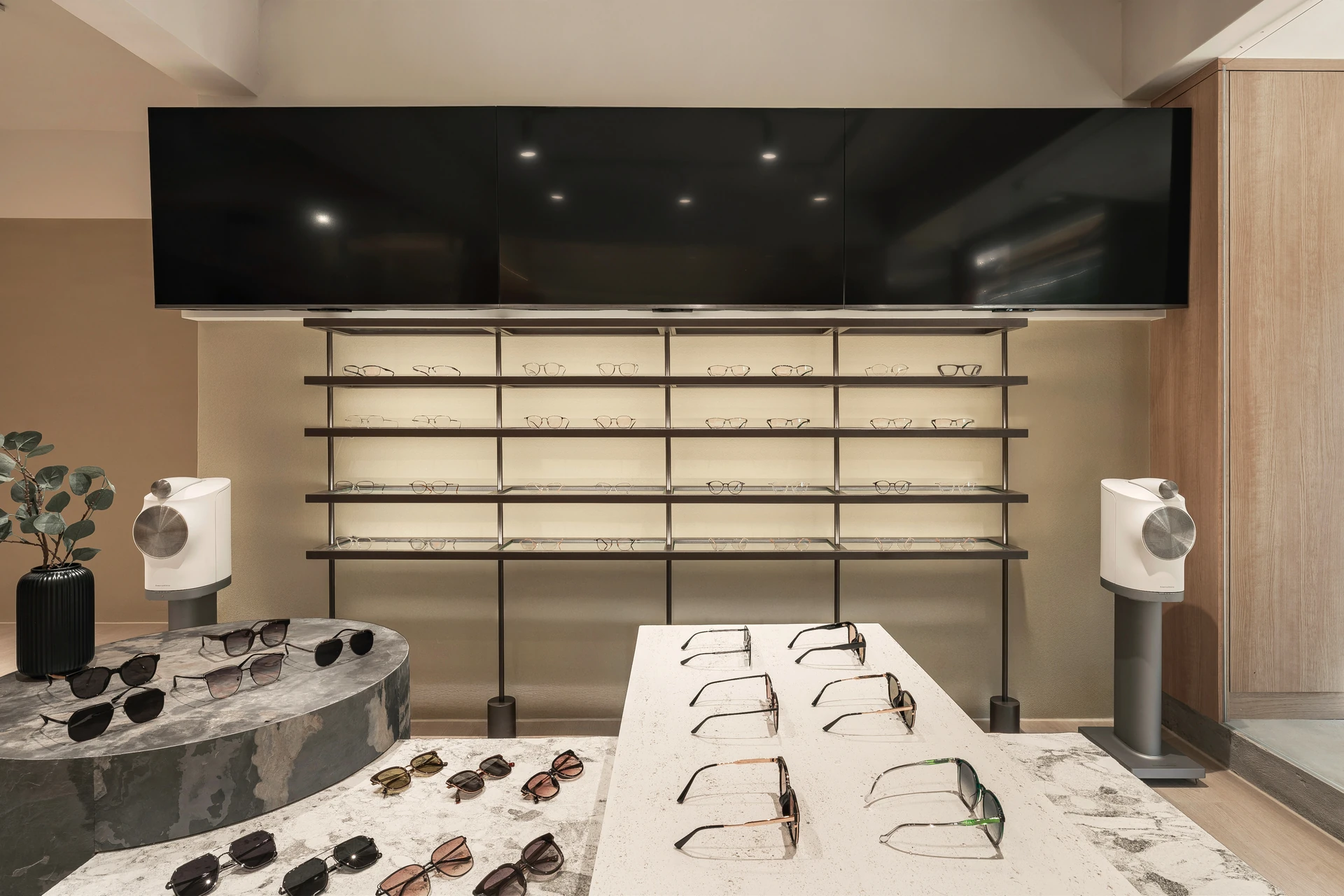 汐止眼鏡店磨石子墨鏡展示島與黑鐵層板背牆、音響端景 — 覺壹設計